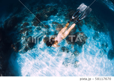 Slim woman freediver swim with fins underwater. Freediving in blue ocean Slim woman freediver swim with fins underwater. Freediving in blue ocean 58117670