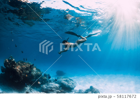 Woman freediver with fins underwater. Freediving and beautiful light in blue ocean 58117672