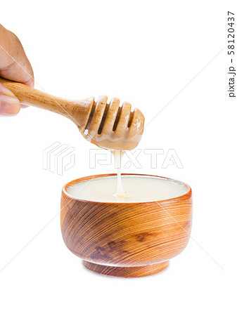 pouring condensed milk into wooden bowl. 58120437