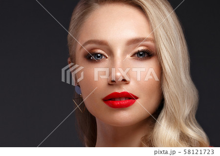 Beautiful blonde in a Hollywood manner with curls, natural makeup and red lips. Beauty face and hair Beautiful blonde in a Hollywood manner with curls, natural makeup and red lips. Beauty face and hair 58121723