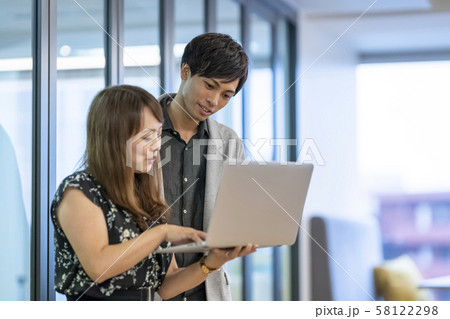 先輩エルダーから優しくパソコン操作を学ぶ若手男性ビジネスマン派遣社員 58122298