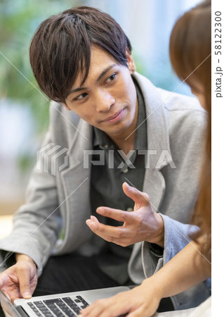 後輩女性社員に優しくパソコン操作を教える若手男性ビジネスマン 58122300