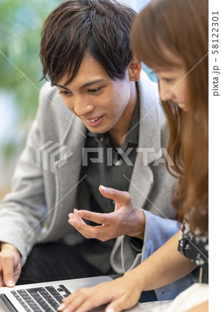 プレゼン資料を既婚女性社員に説明し反応を見る独身男性ビジネスマン 58122301