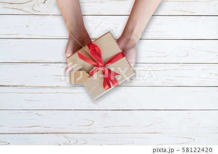 Woman hand holding gift box on wood plank and Woman hand holding gift box on wood plank and 58122420