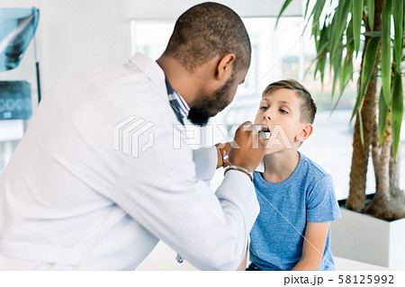 Close-up Of A Young male African Doctor Checking His Patient's Boy Throat In Clinic 58125992