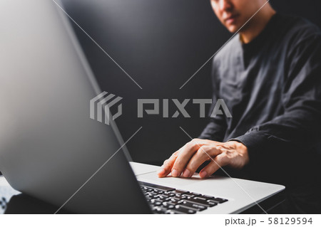 attractive asian man in black using laptop computer in modern home office attractive asian man in black using laptop computer in modern home office 58129594