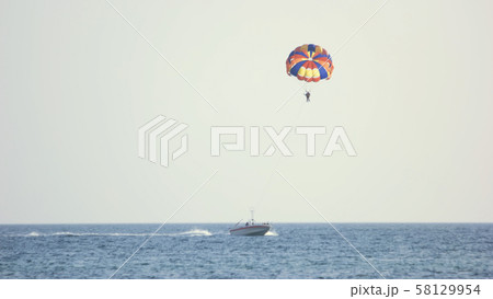 Couple of tourists flying with parachute over the sea. 58129954