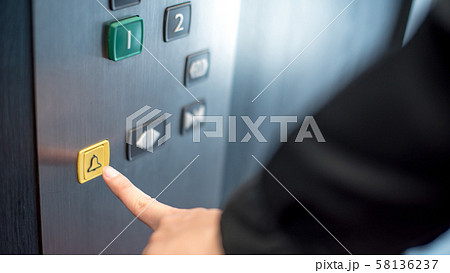 Male hand pressing on emergency button in elevator 58136237