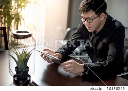 Asian businessman using digital tablet in office Asian businessman using digital tablet in office 58136246