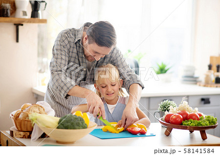 Father and daughter slicing peppers before making stew Father and daughter slicing peppers before making stew 58141584