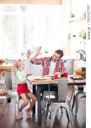 Daughter giving high five to father while having yummy breakfast Daughter giving high five to father while having yummy breakfast 58142707