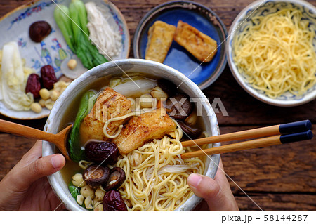 woman hand hold Vietnamese vegan noodles soup on ingredients food background 58144287