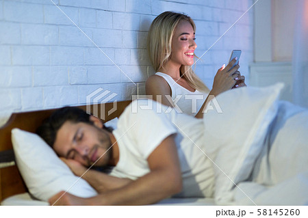 Cheating Wife Chatting On Cellphone While Husband Sleeping In Bedroom 58145260