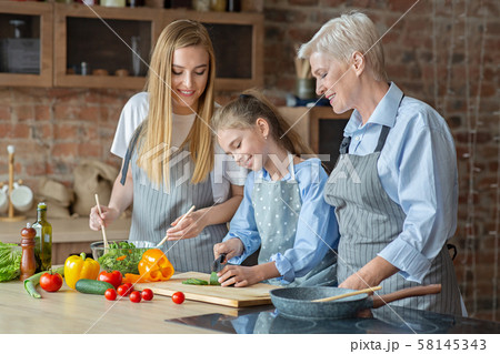 Adult ladies teaching little girl how to cook 58145343