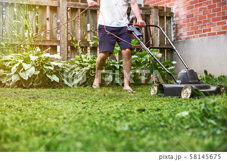 cutting overgrown grass with old fashioned lawn 58145675
