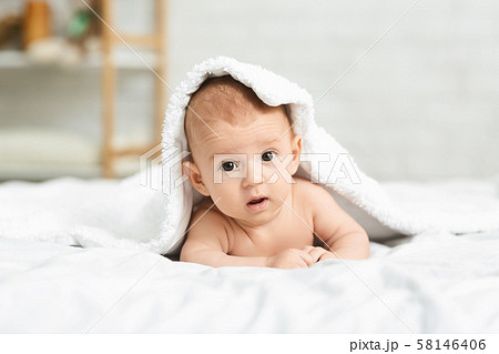 Portrait of cute newborn boy peeking out from under blanket 58146406