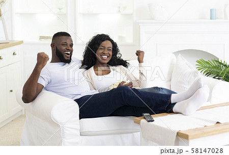 Black Millennial Couple Watching Sports On Television And Cheering Black Millennial Couple Watching Sports On Television And Cheering 58147028