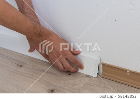 Worker installing plastic skirting board 58148852
