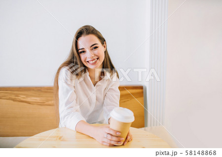 Happy young woman in a cafe with a cup of coffee. 58148868