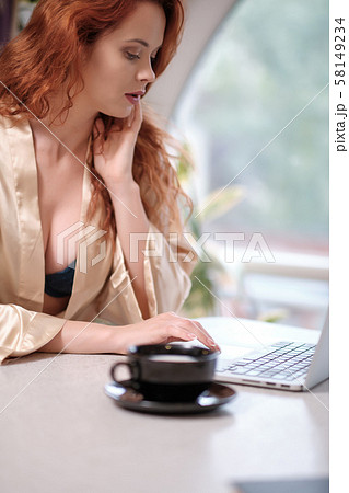 Woman in a bathrobe works on a laptop at home Woman in a bathrobe works on a laptop at home 58149234