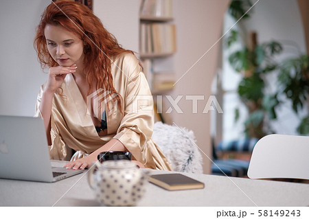 Woman in a bathrobe works on a laptop at home Woman in a bathrobe works on a laptop at home 58149243
