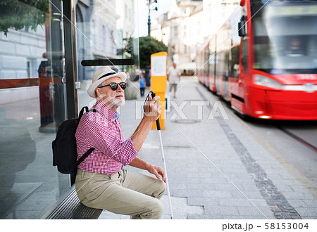 Senior blind man with white cane waiting for public transport in city. Senior blind man with white cane waiting for public transport in city. 58153004