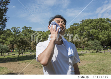 代々木公園で運動の後に汗を拭く中年の男性 58154845