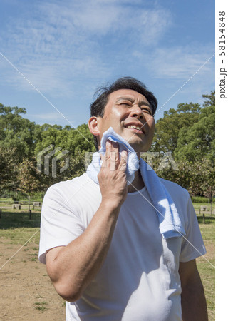 代々木公園で運動の後に汗を拭く中年の男性 58154848