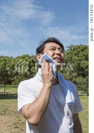 代々木公園で運動の後に汗を拭く中年の男性 代々木公園で運動の後に汗を拭く中年の男性 58154850