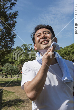 代々木公園で運動の後に汗を拭く中年の男性 代々木公園で運動の後に汗を拭く中年の男性 58154859