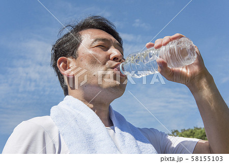代々木公園で運動後に熱中症対策のためお水を飲む中年の男性 58155103