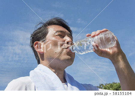 代々木公園で運動後に熱中症対策のためお水を飲む中年の男性 58155104