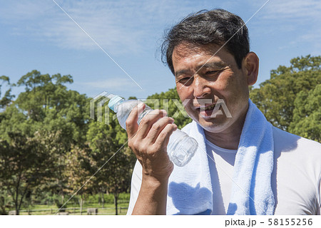 代々木公園で運動の後に熱中症対策のためお水を飲もうとしている中年の男性 58155256