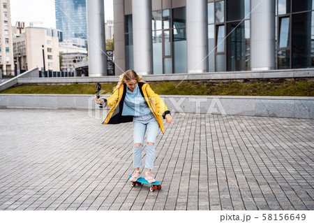 Blond female hipster woman riding on the longboard in the street at city. Blond female hipster woman riding on the longboard in the street at city. 58156649
