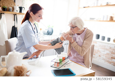 Nurse measuring pressure for grey-haired pensioner 58159345