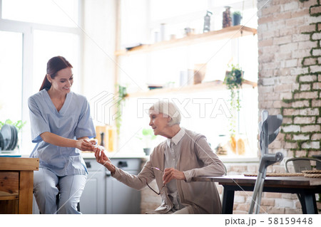Grey-haired aged woman taking pills from nurse 58159448