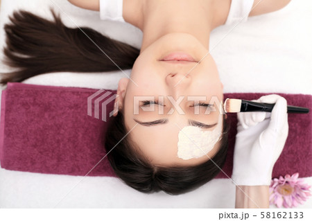Cosmetology spa facial. Beautiful brunette in a spa salon 58162133