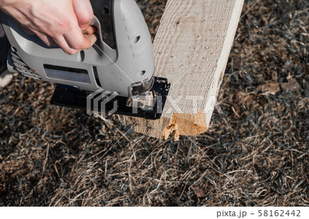 a man saws an electric jigsaw board 58162442