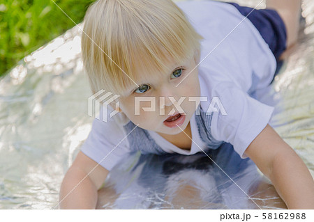 Happy little boy on a green lawn in a park. 58162988