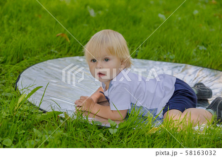 Happy little boy on a green lawn in a park. 58163032