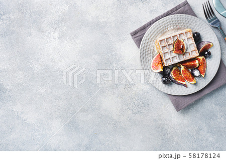 Traditional Belgian waffles with powdered sugar grapes and figs. Cozy homemade Breakfast. Gray concrete background. Copy space. 58178124