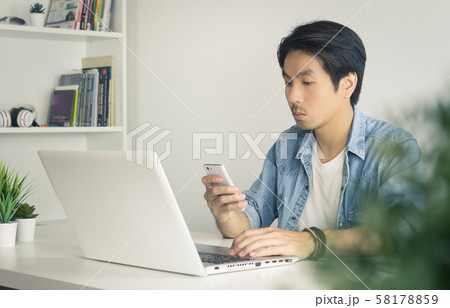 Portrait Asian Casual Businessman Sending Message to Colleague by Smartphone in Vintage Tone Portrait Asian Casual Businessman Sending Message to Colleague by Smartphone in Vintage Tone 58178859