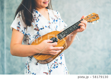 Happy woman musician playing ukulele in studio. Happy woman musician playing ukulele in studio. 58179130