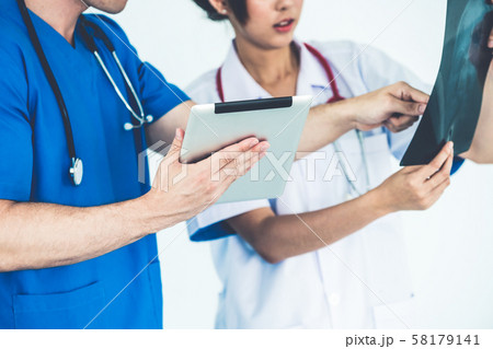 Doctors working with x ray film of patient head. Doctors working with x ray film of patient head. 58179141