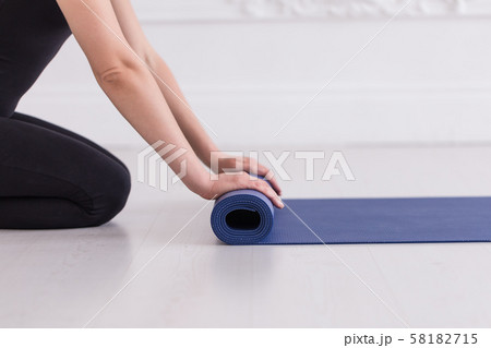 Closeup of young women's hands rolling up the blue carpet 58182715