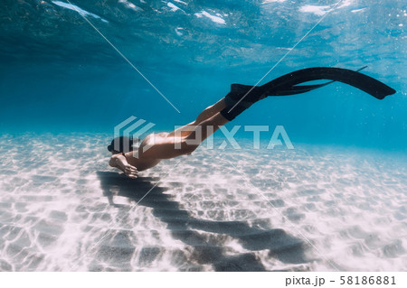 Naked woman freediver glides over sandy bottom. Beautiful woman swim with fins Naked woman freediver glides over sandy bottom. Beautiful woman swim with fins 58186881