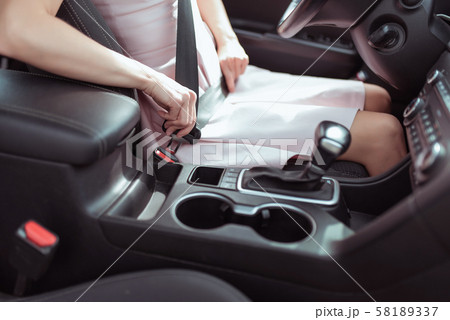 Close-up, a girl in pink dress in car interior fastens her seat belt, interior of car automatic 58189337