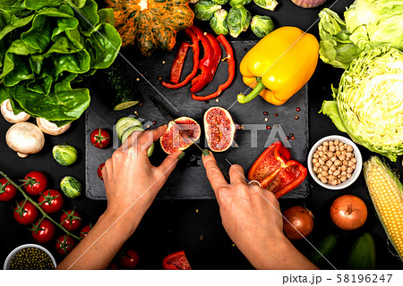 Female hands cut vegetables on a black background. Cooking vegetarian food. Top view. 58196247