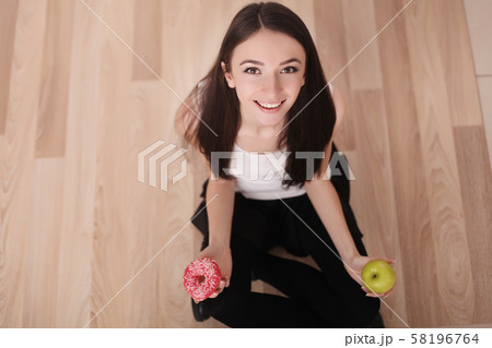 Diet. Woman Measuring Body Weight On Weighing Scale Holding Donut and apple. Sweets Are Unhealthy Diet. Woman Measuring Body Weight On Weighing Scale Holding Donut and apple. Sweets Are Unhealthy 58196764