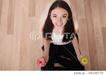 Diet. Woman Measuring Body Weight On Weighing Scale Holding Donut and apple. Sweets Are Unhealthy 58196770